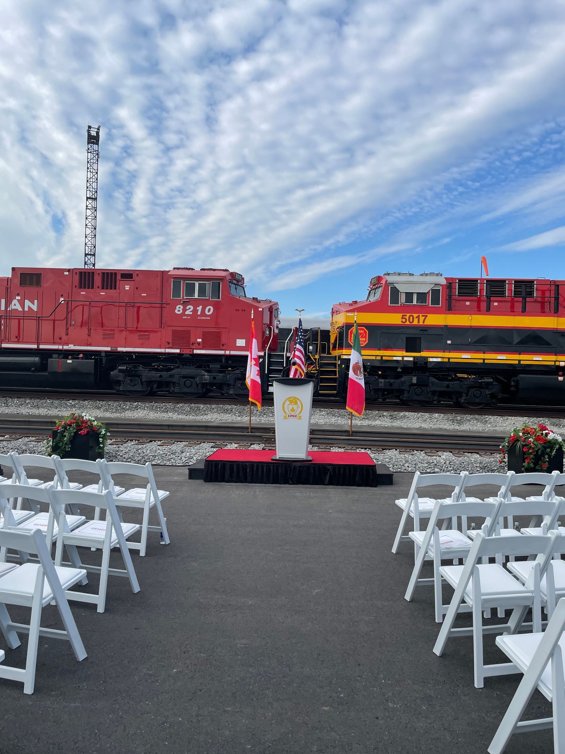 A podium is set up in front of two canadian trains