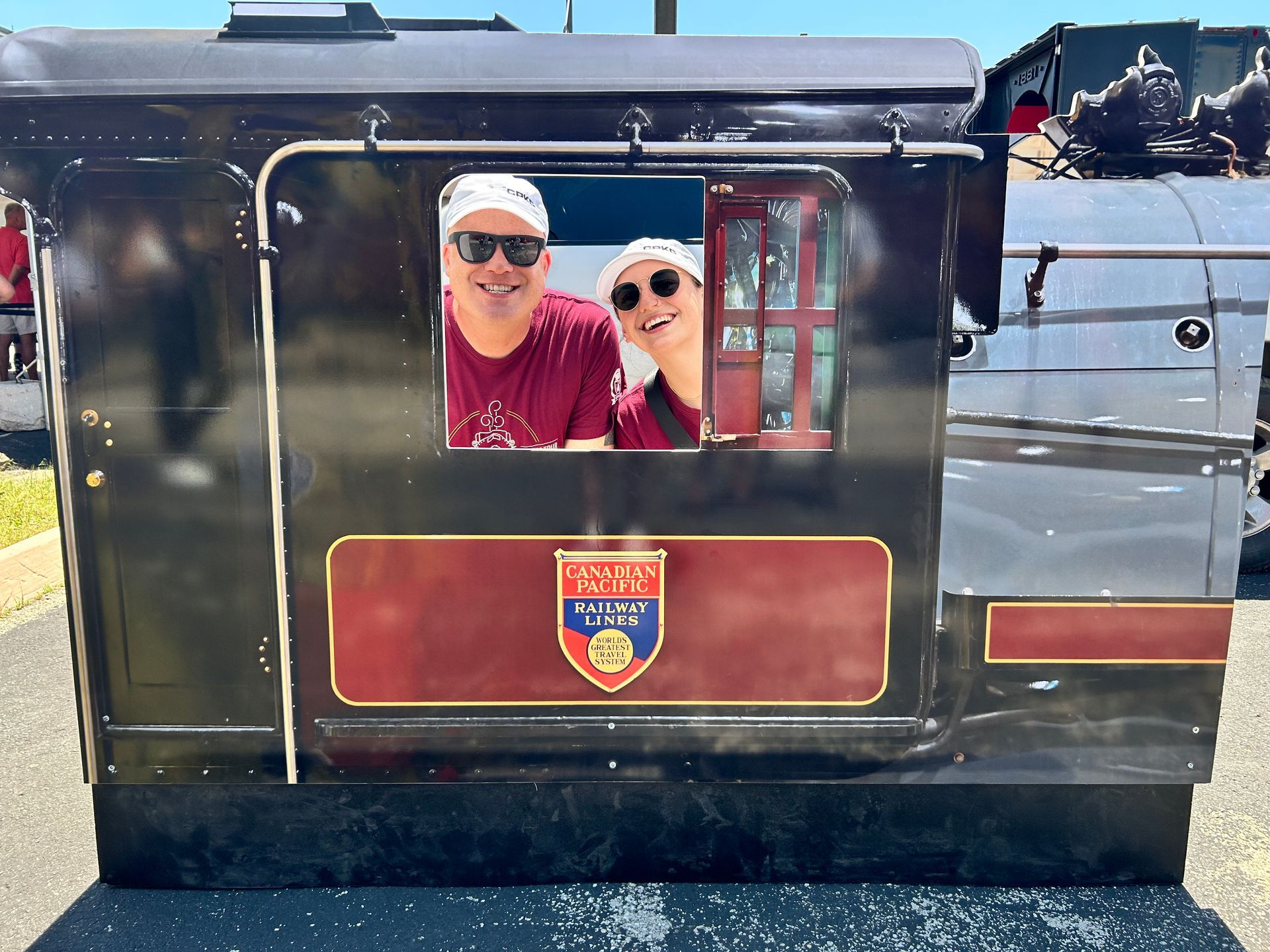 A man and woman are posing for a picture in the window of a train