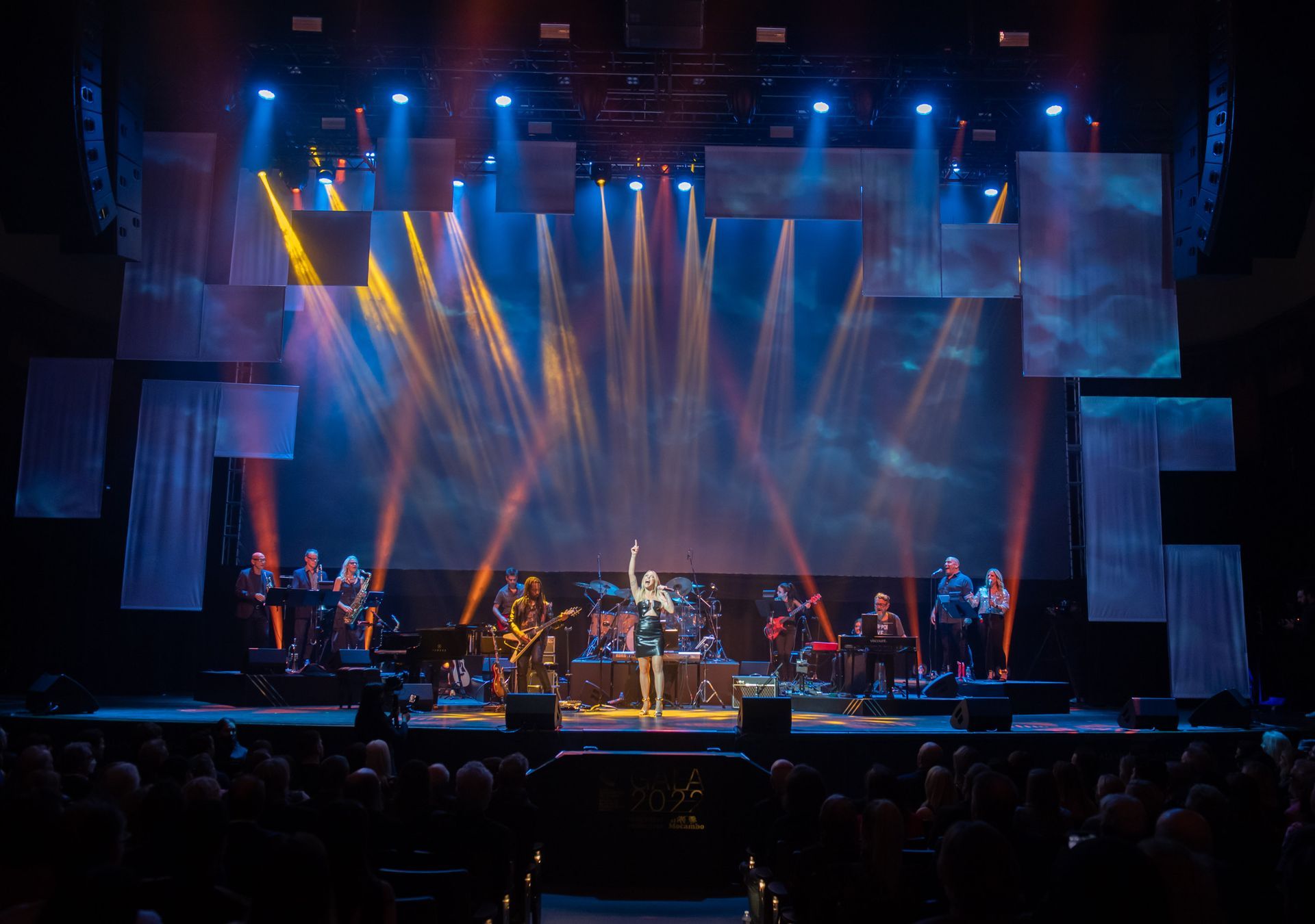 A group of people are standing on a stage in front of a large screen.