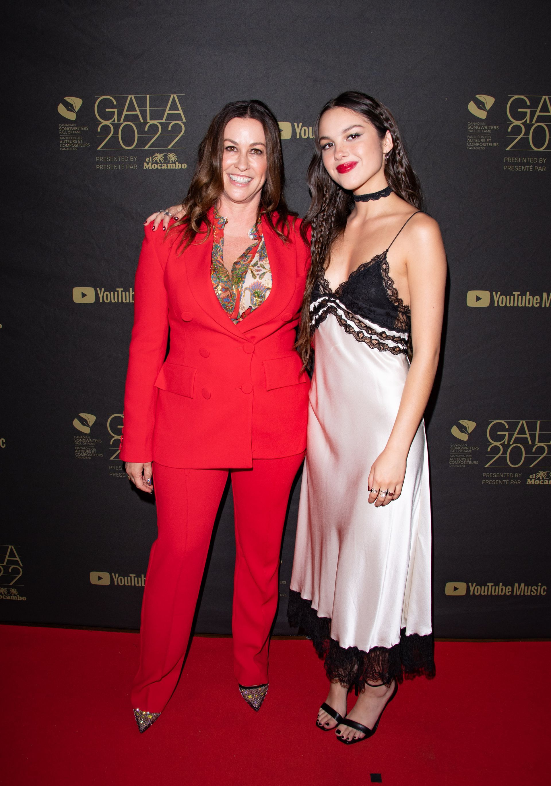 Two women are standing next to each other on a red carpet.