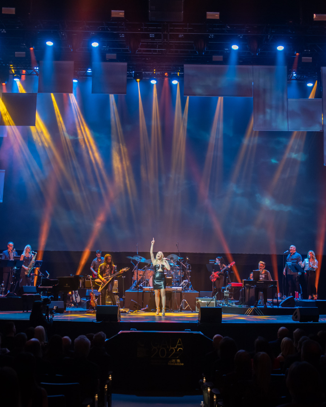 A woman singing into a microphone on a stage in front of a crowd