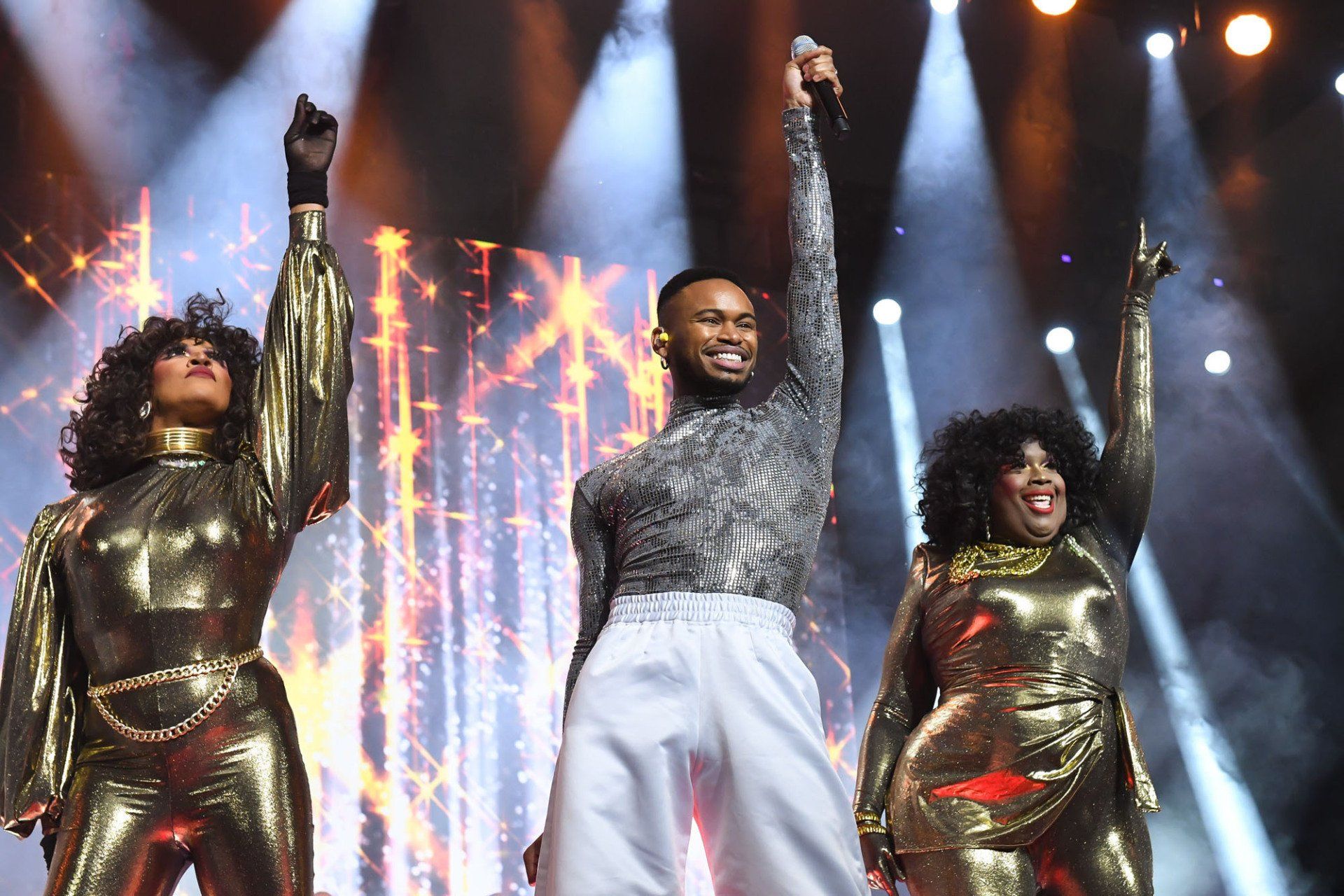 A group of people are standing on a stage with their arms in the air.