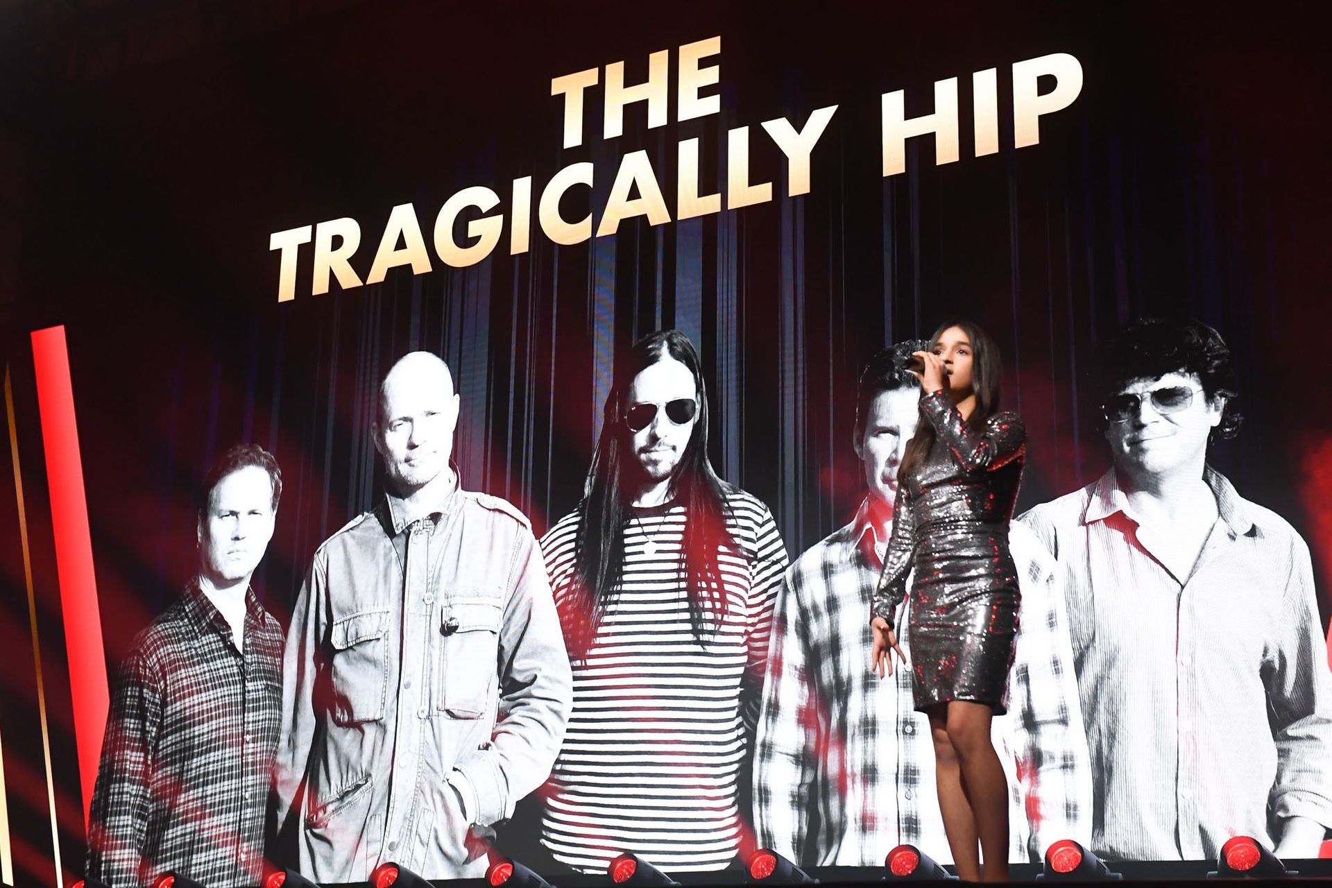 A group of people standing in front of a sign that says the tragically hip