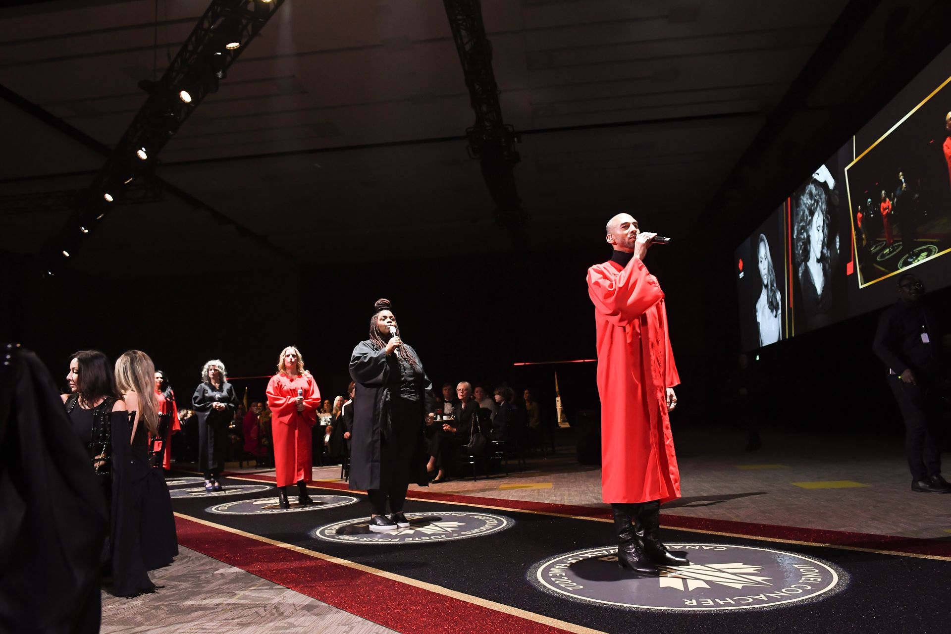 A group of people are standing on a stage in front of a large screen.