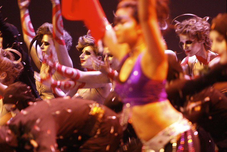 A group of women are dancing on a stage with their arms in the air.