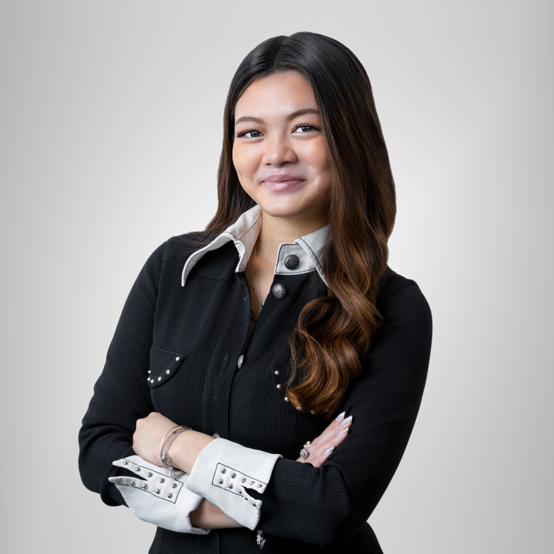 A woman in a black shirt and white collar is standing with her arms crossed.