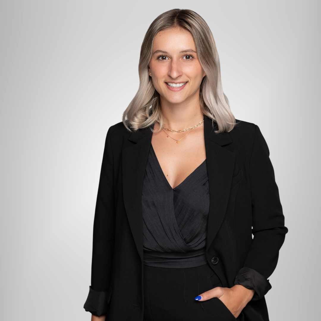 A woman wearing a black jacket and a black top is standing with her hands in her pockets.