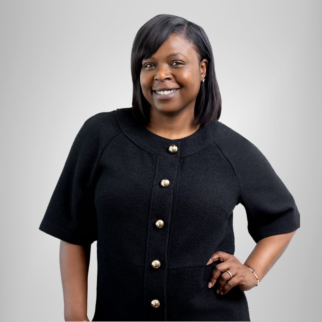A woman wearing a pink jacket and a white shirt is smiling.