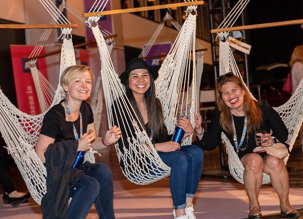 Three women are sitting in hammocks holding bottles of water.