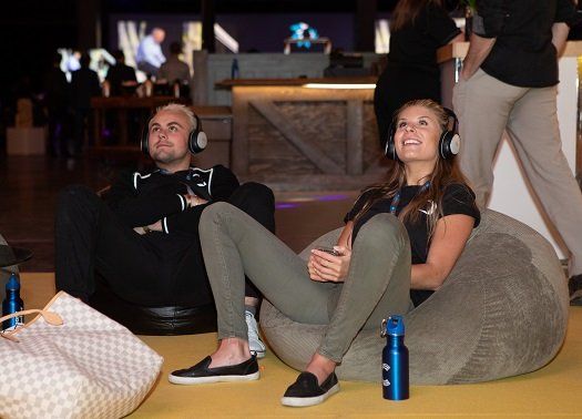 A man and a woman are sitting on bean bags wearing headphones