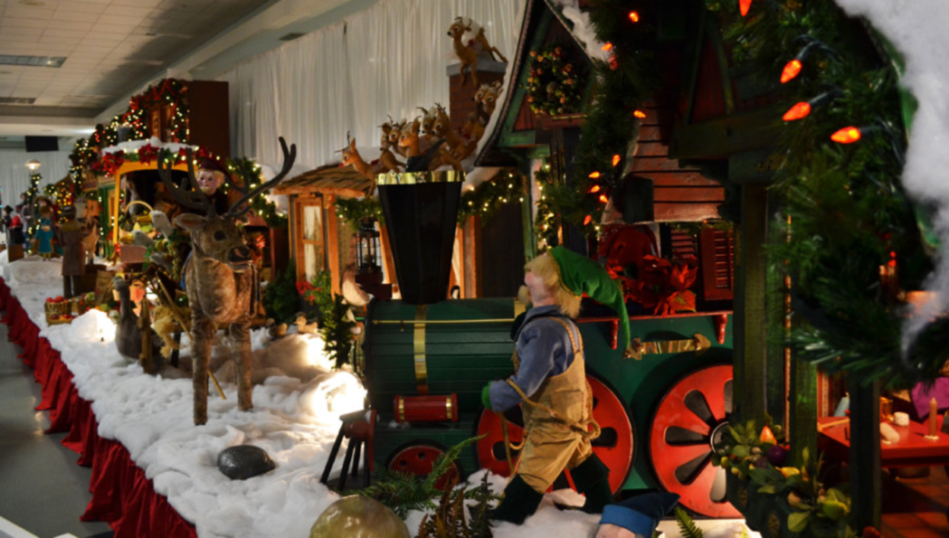 A christmas display with a train , elves , and a reindeer.