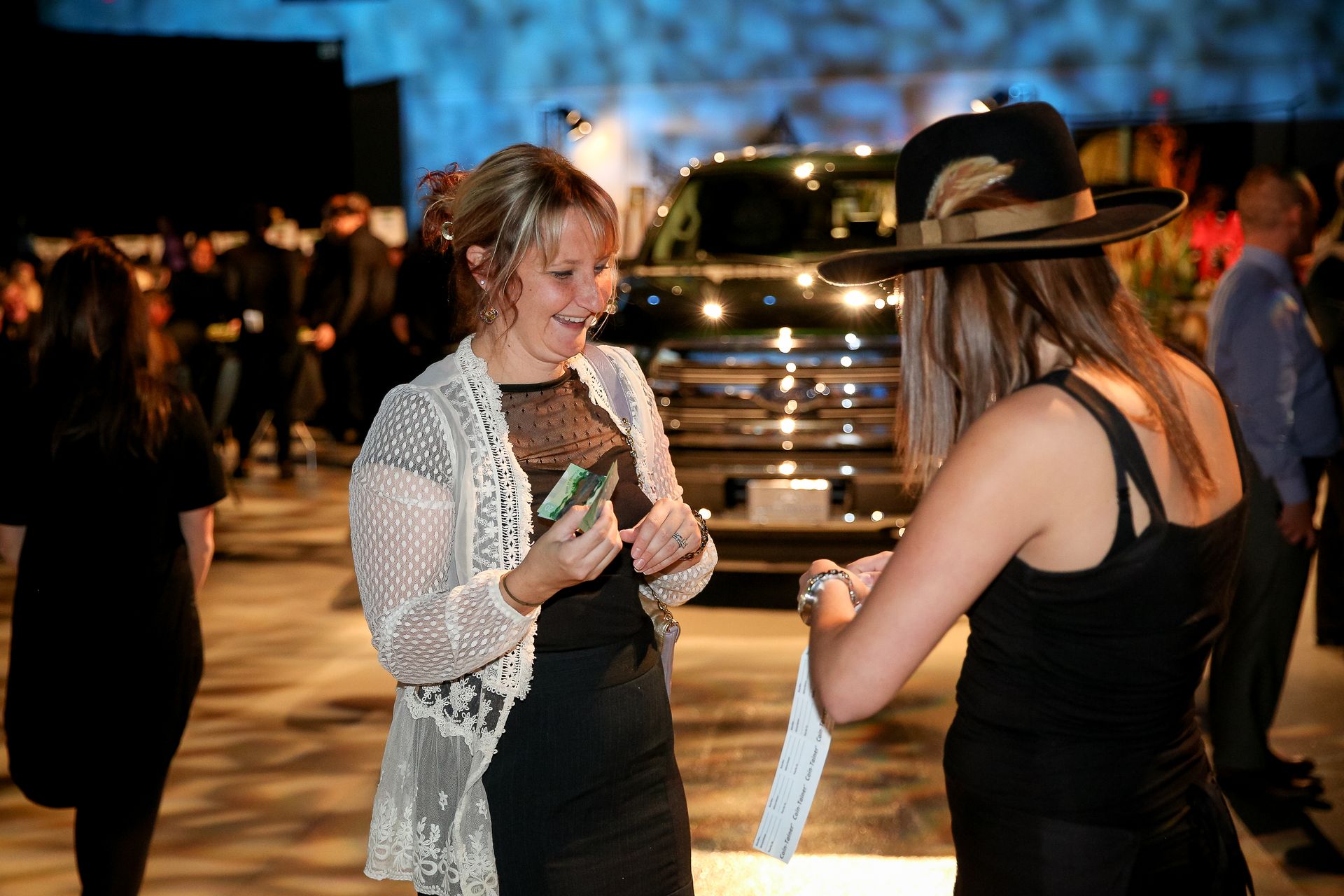 Two women are talking to each other in front of a car