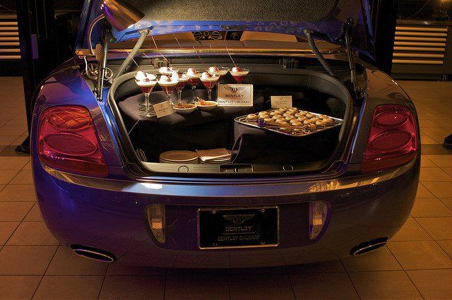 The trunk of a car is filled with plates of food and drinks.