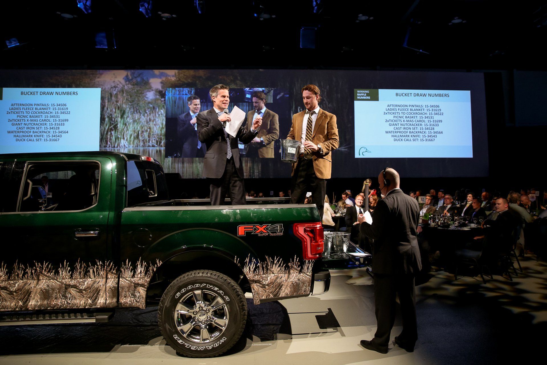 A group of men are standing around a green ford truck