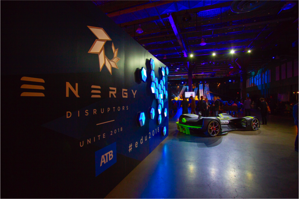 A race car is parked in front of a wall with a sign on it.