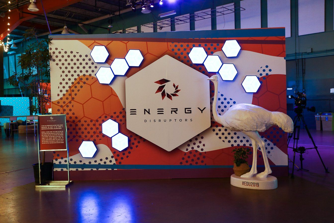 A statue of a bird is standing in front of a wall that says energy.