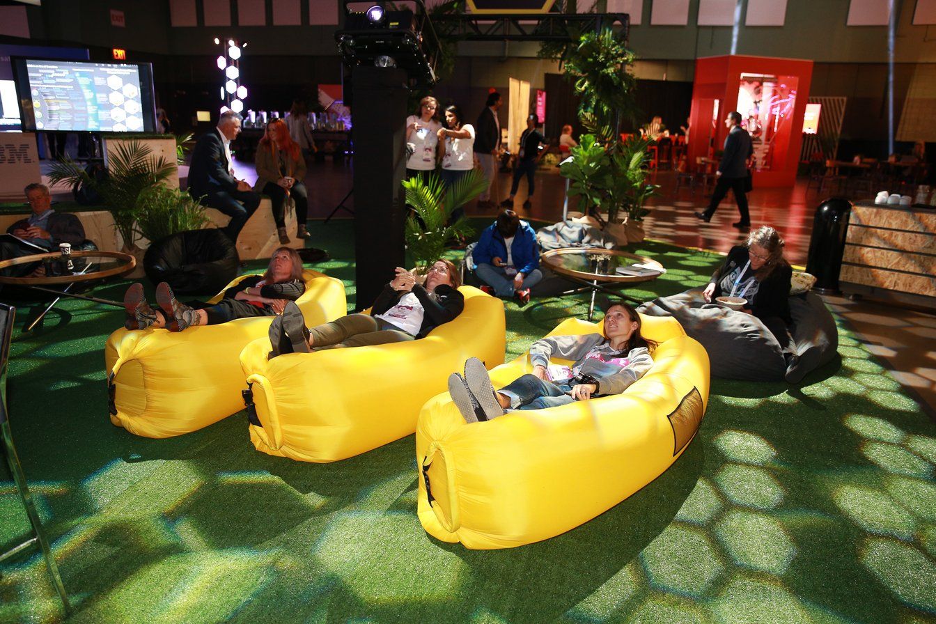 A group of people are laying on yellow bean bag chairs.
