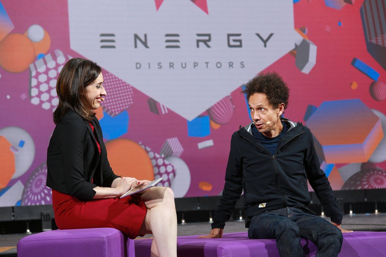 A woman is sitting on a purple couch talking to a man.