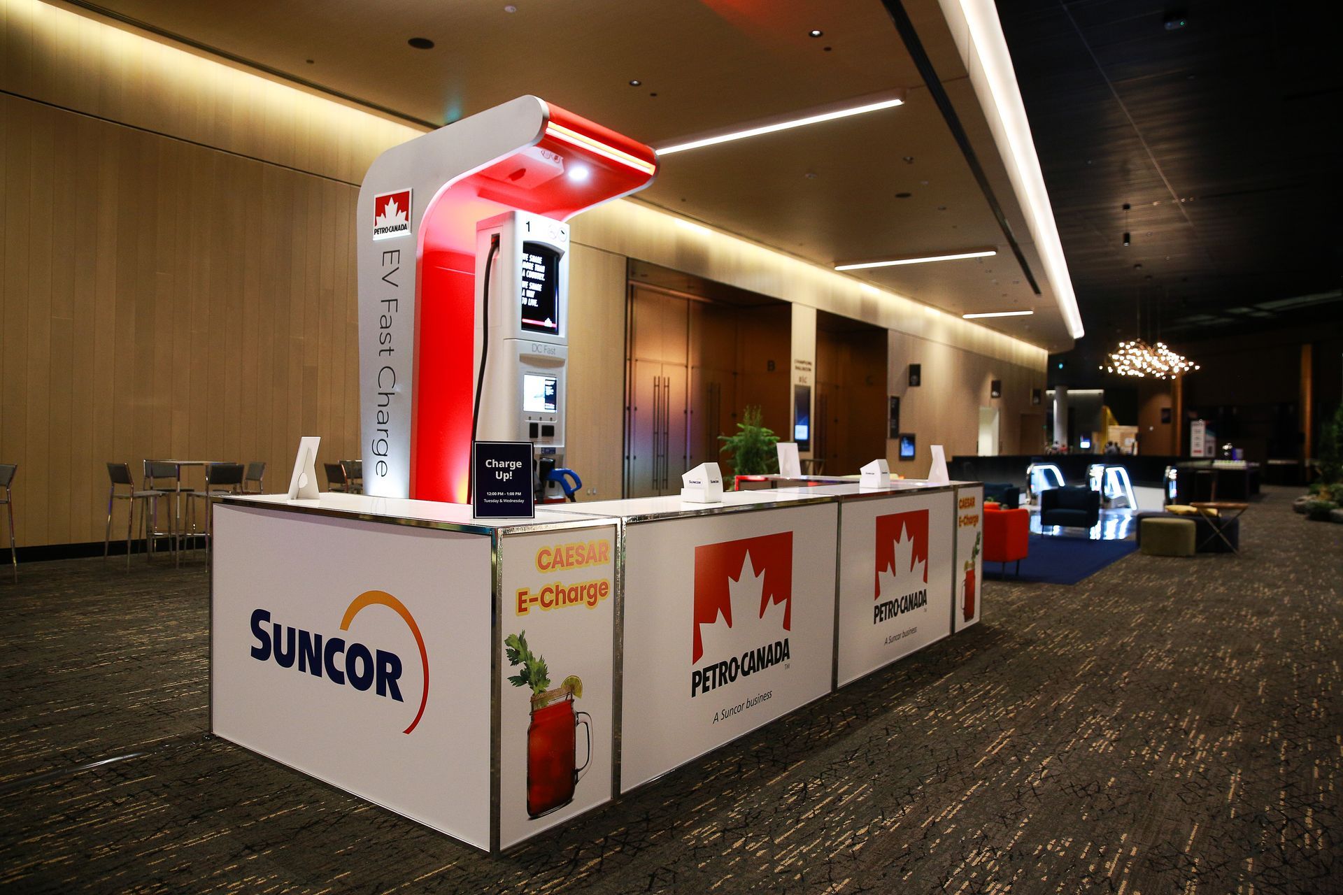 Suncor E-Charge station in a lobby. White and red kiosk with branding, and promotional display.