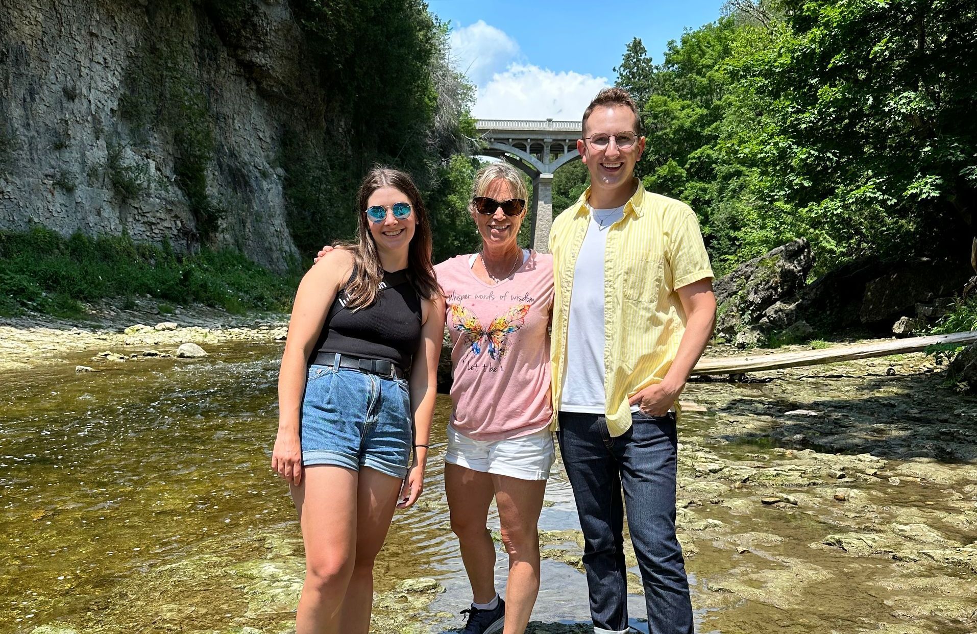 Three people are standing next to each other in front of a river.