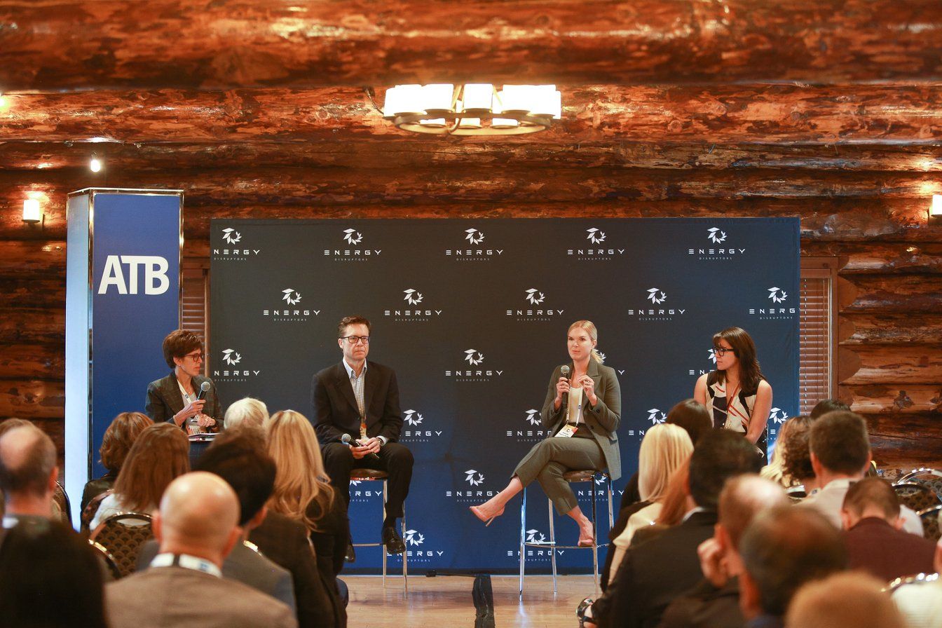 A group of people are sitting in front of a wooden wall.