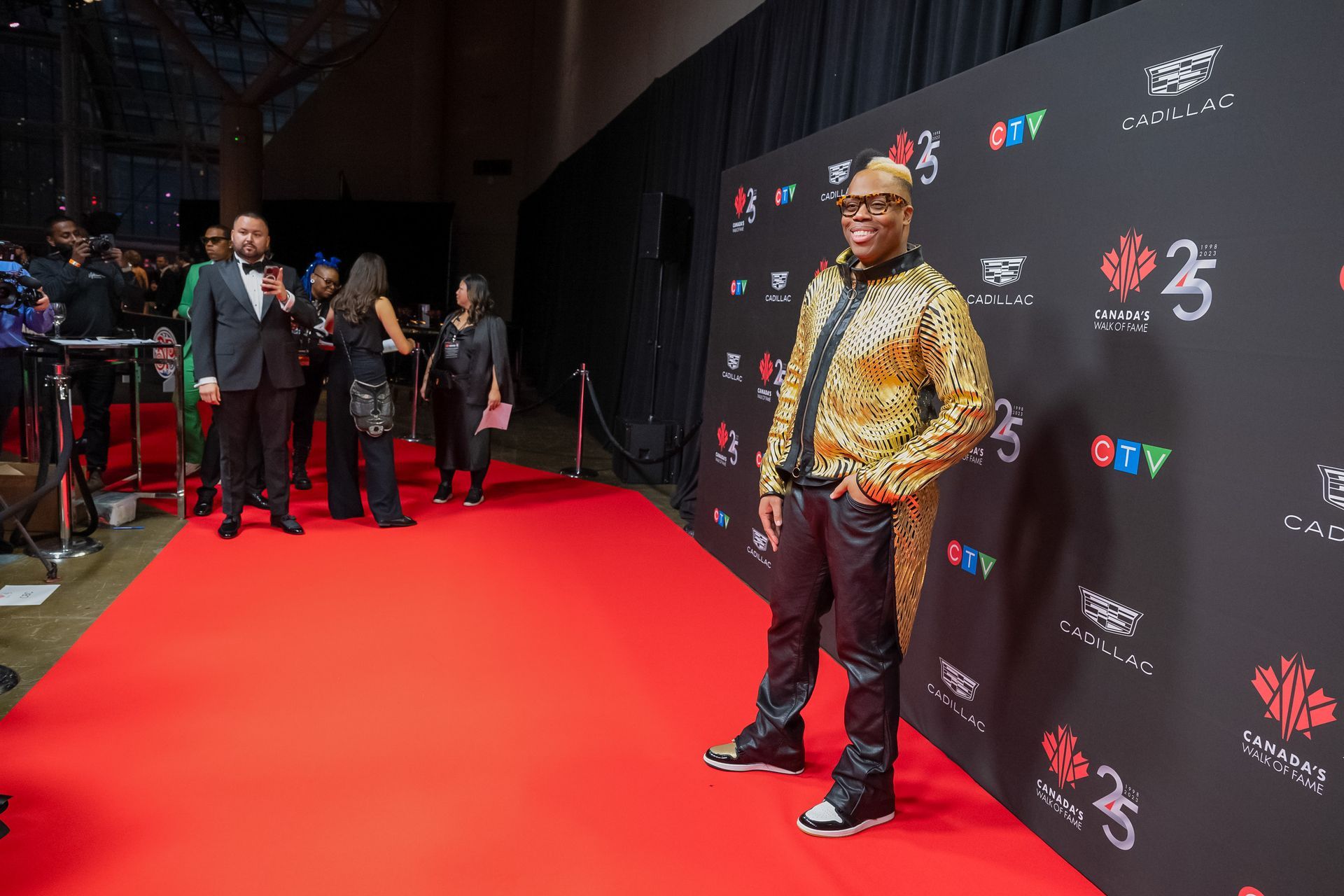 A man in a gold jacket is standing on a red carpet.