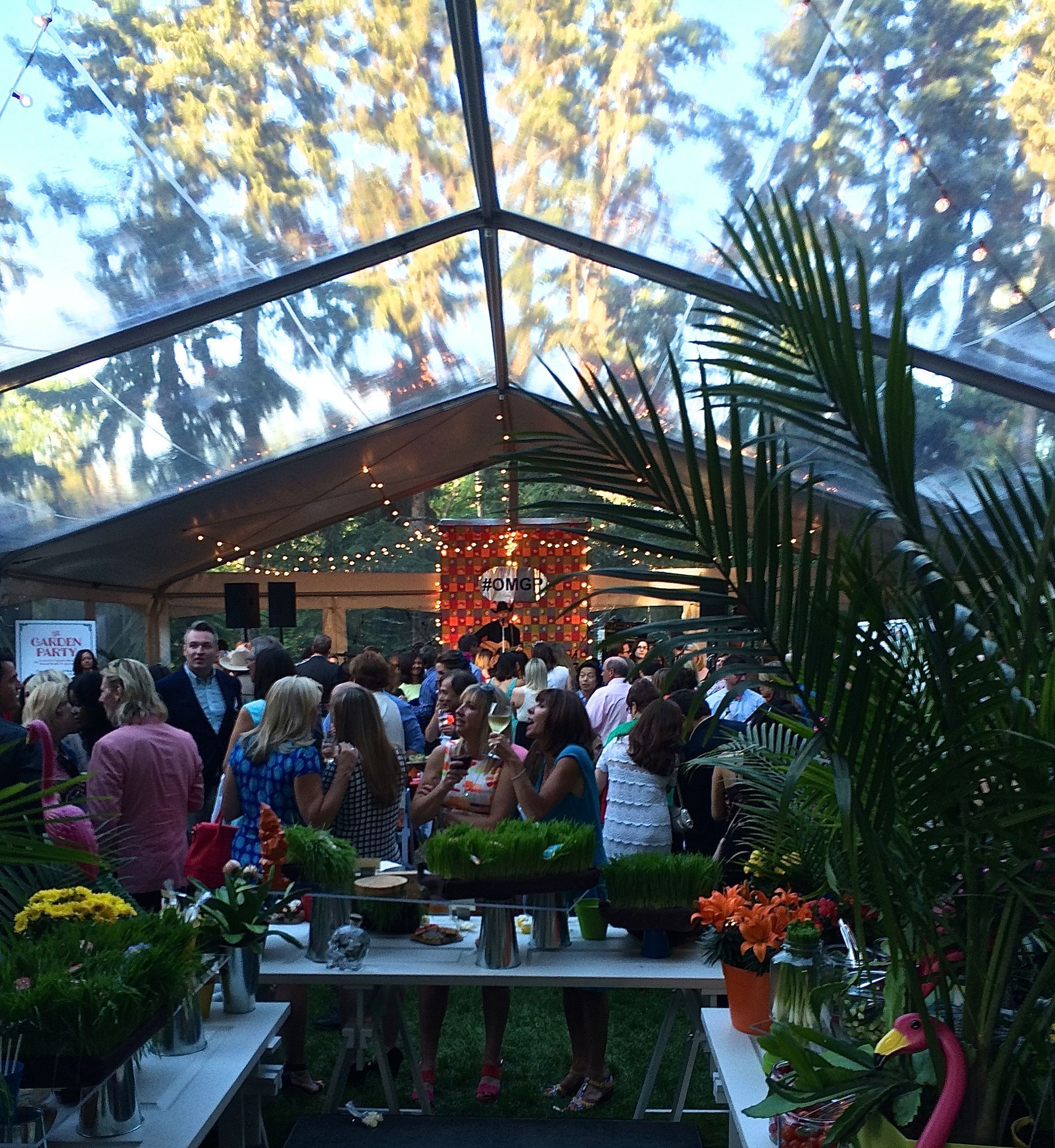 A group of people are gathered under a clear tent.