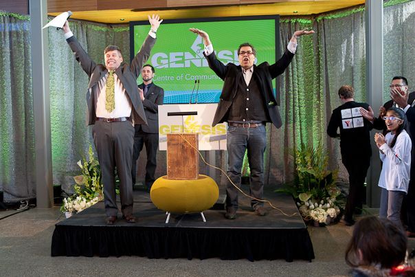 Two men are standing on a stage with their arms in the air.