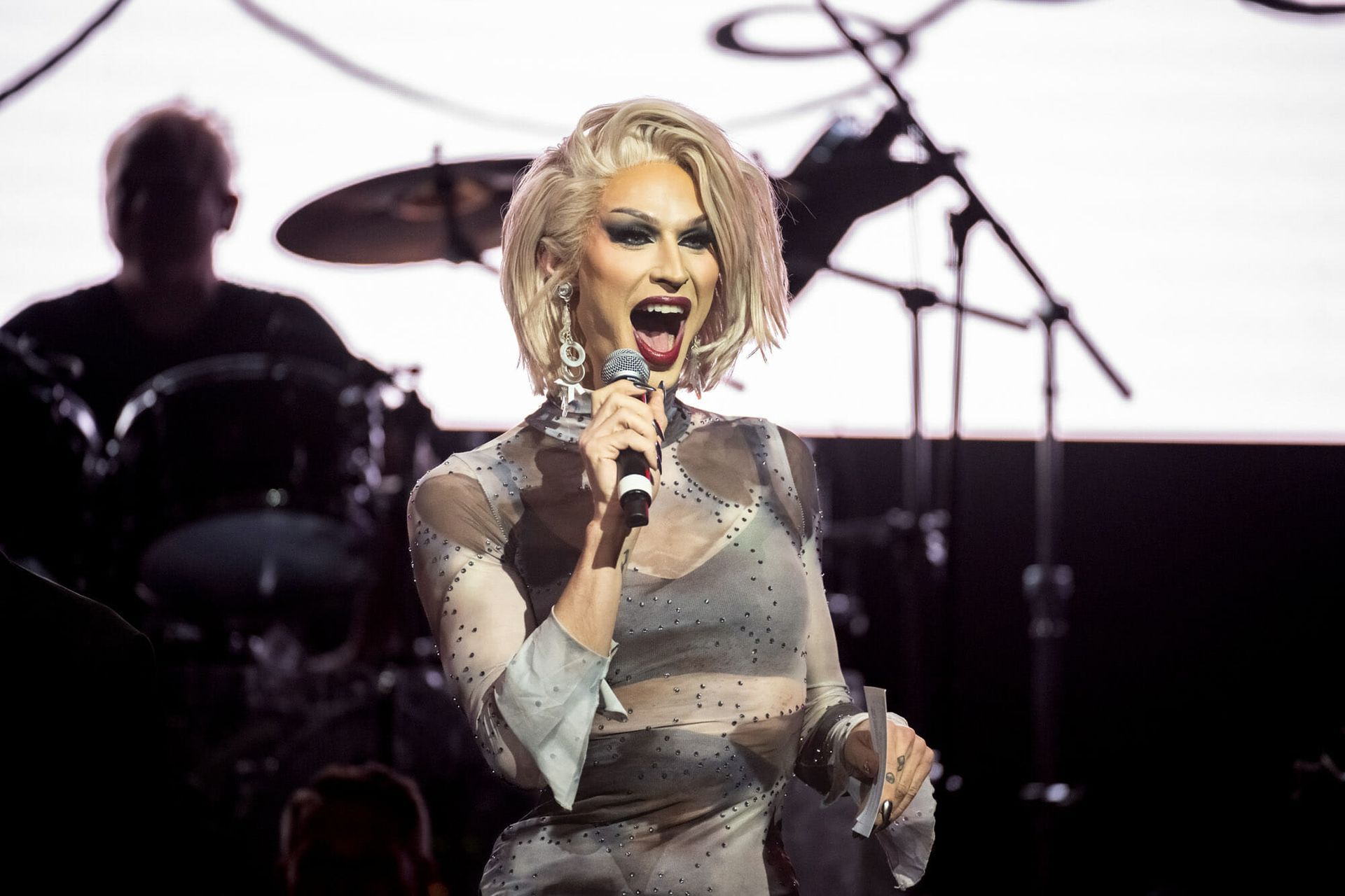 A woman is singing into a microphone on a stage.