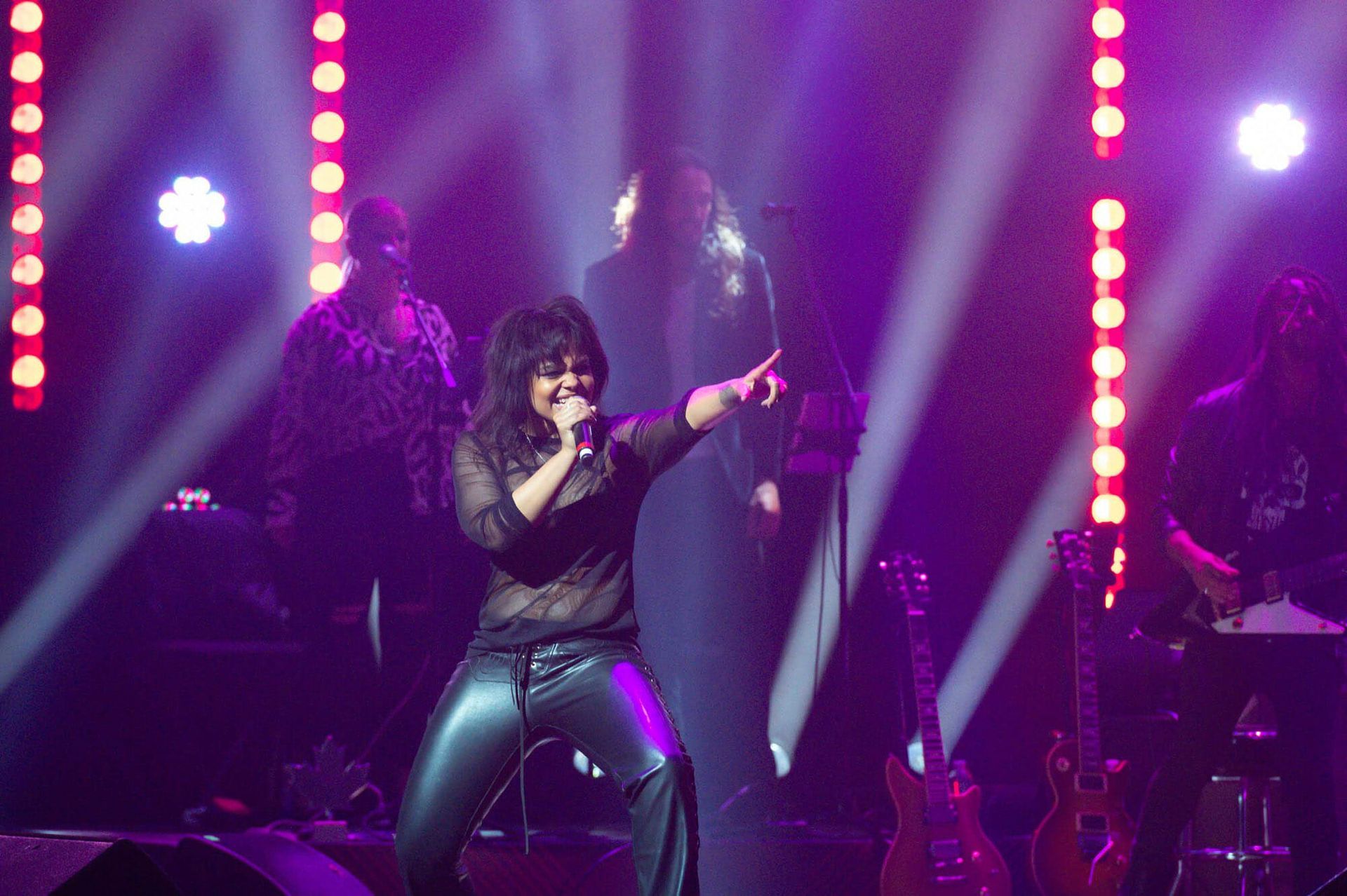 A woman is singing into a microphone on a stage.