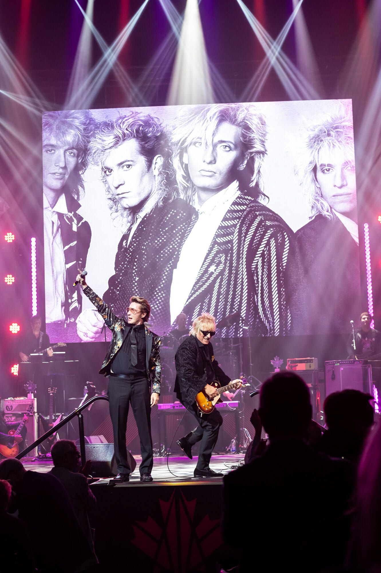 A group of men are standing on a stage in front of a large screen.