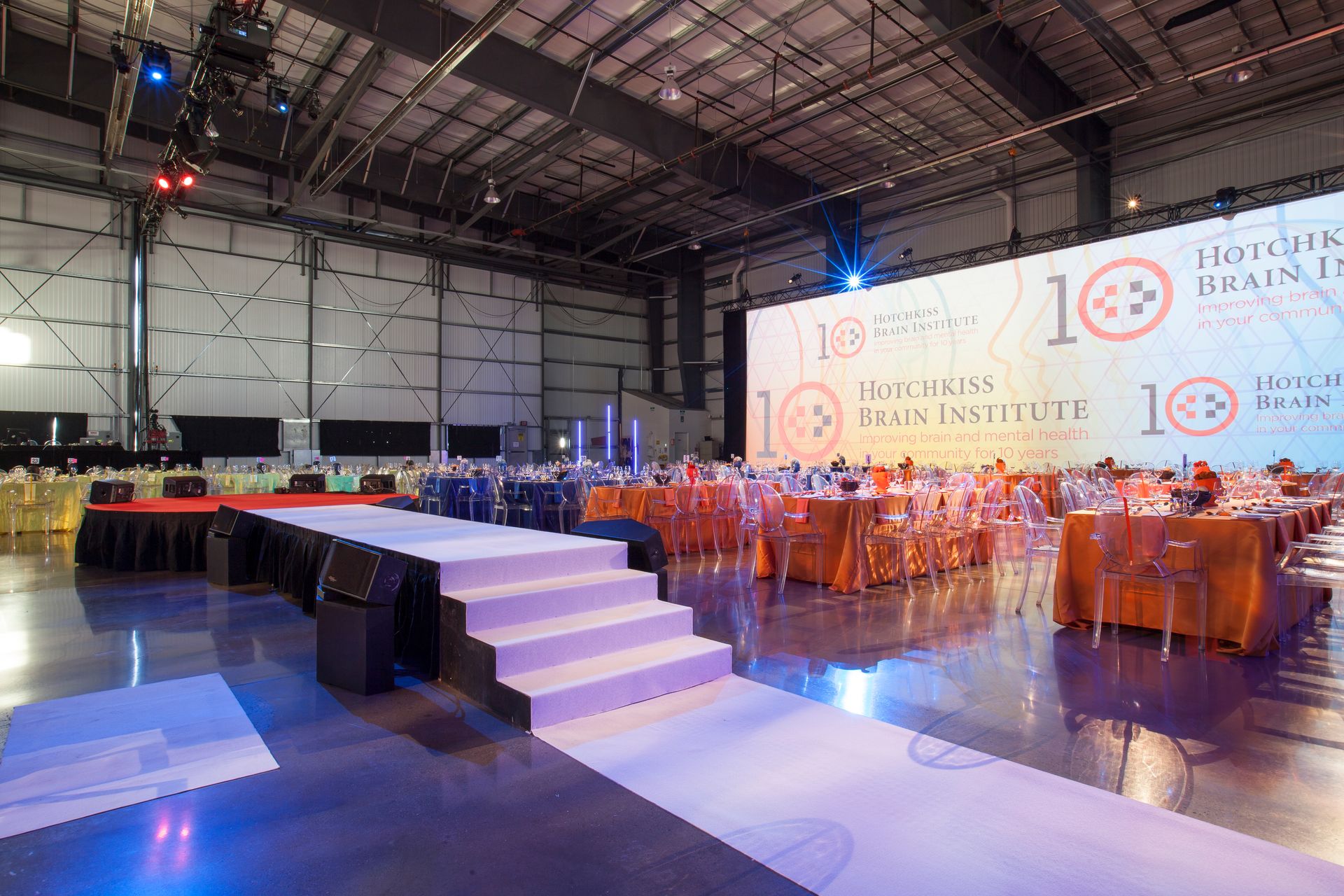 There is a stage in the middle of the room with tables and chairs.