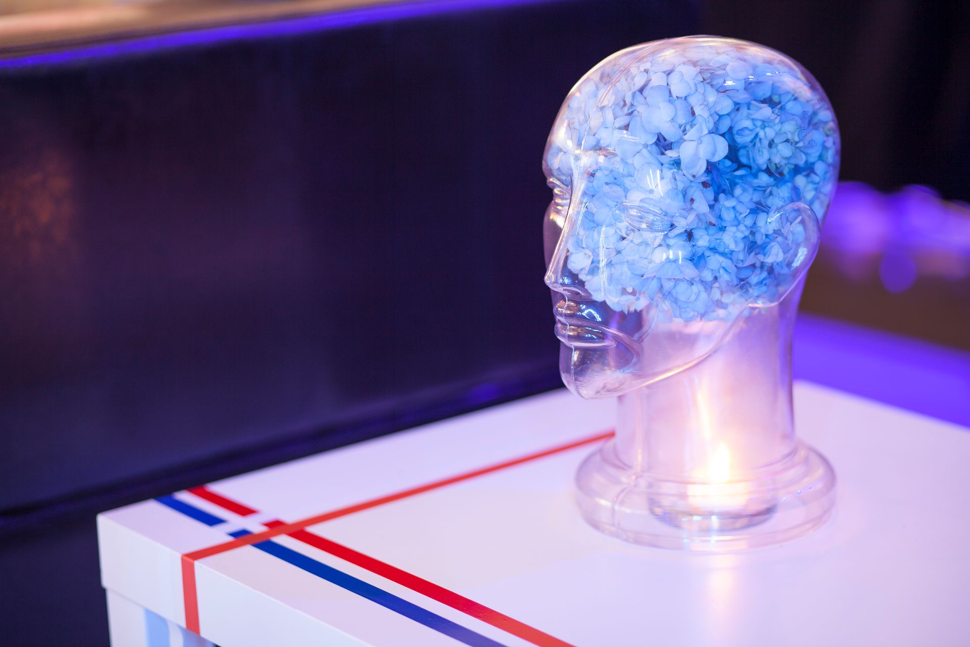 A glass head with blue flowers in it is on a table.