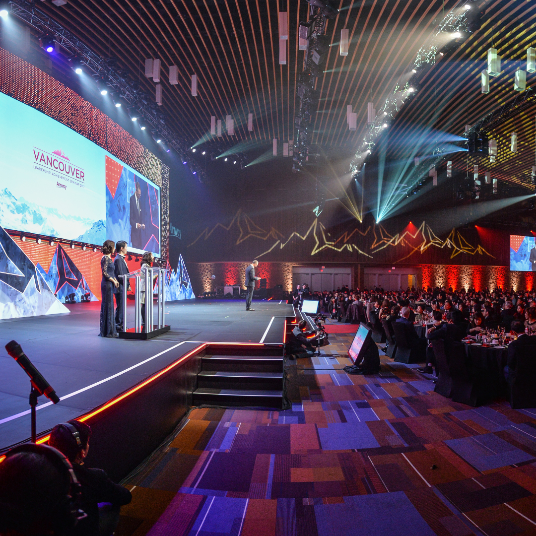A group of people are standing on a stage in a large auditorium