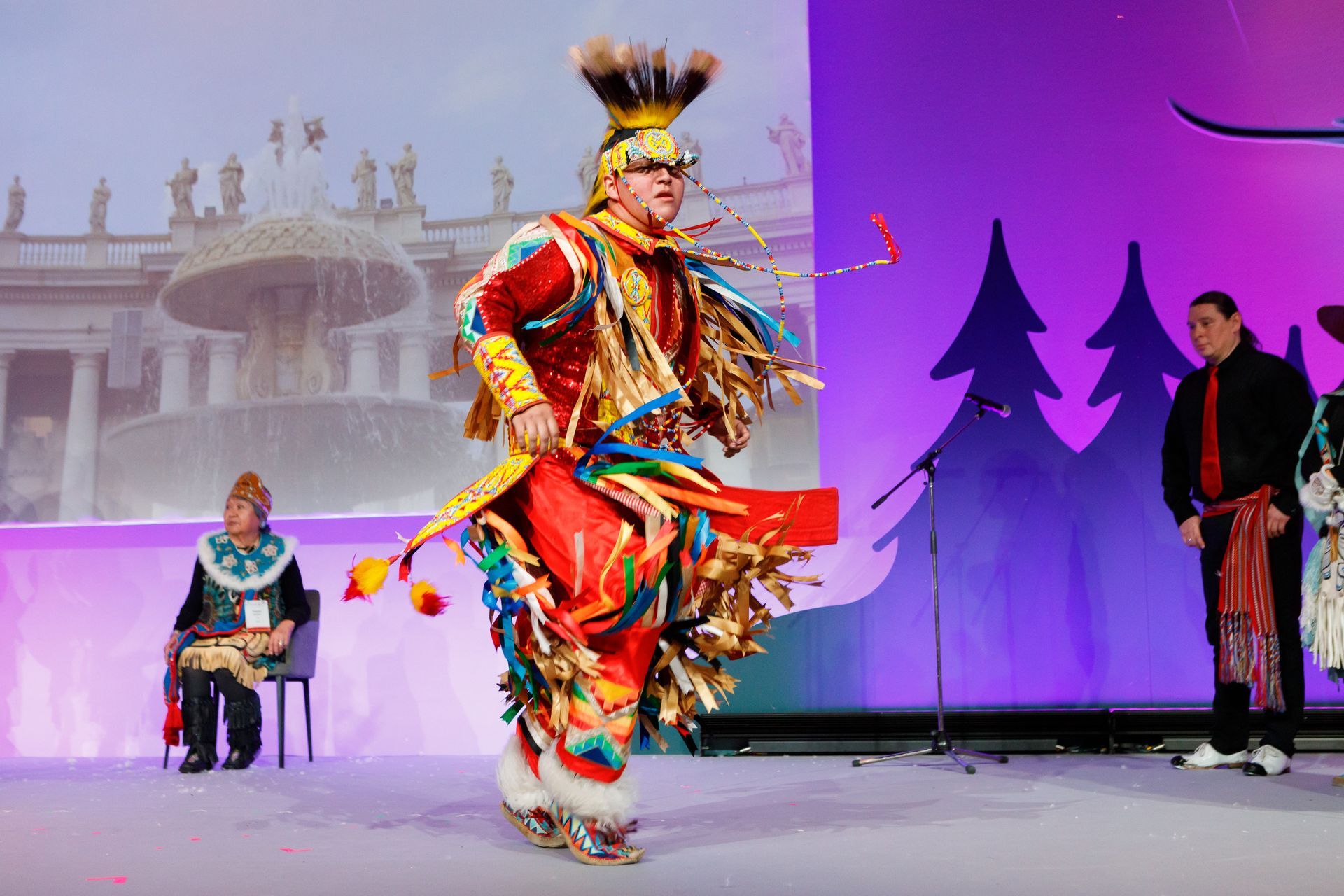 A man in a native american costume is dancing on a stage