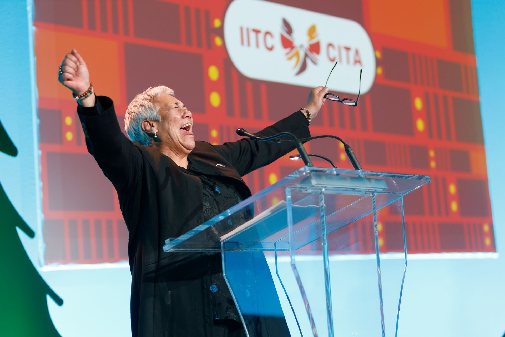 A man is standing at a podium with his arms in the air.