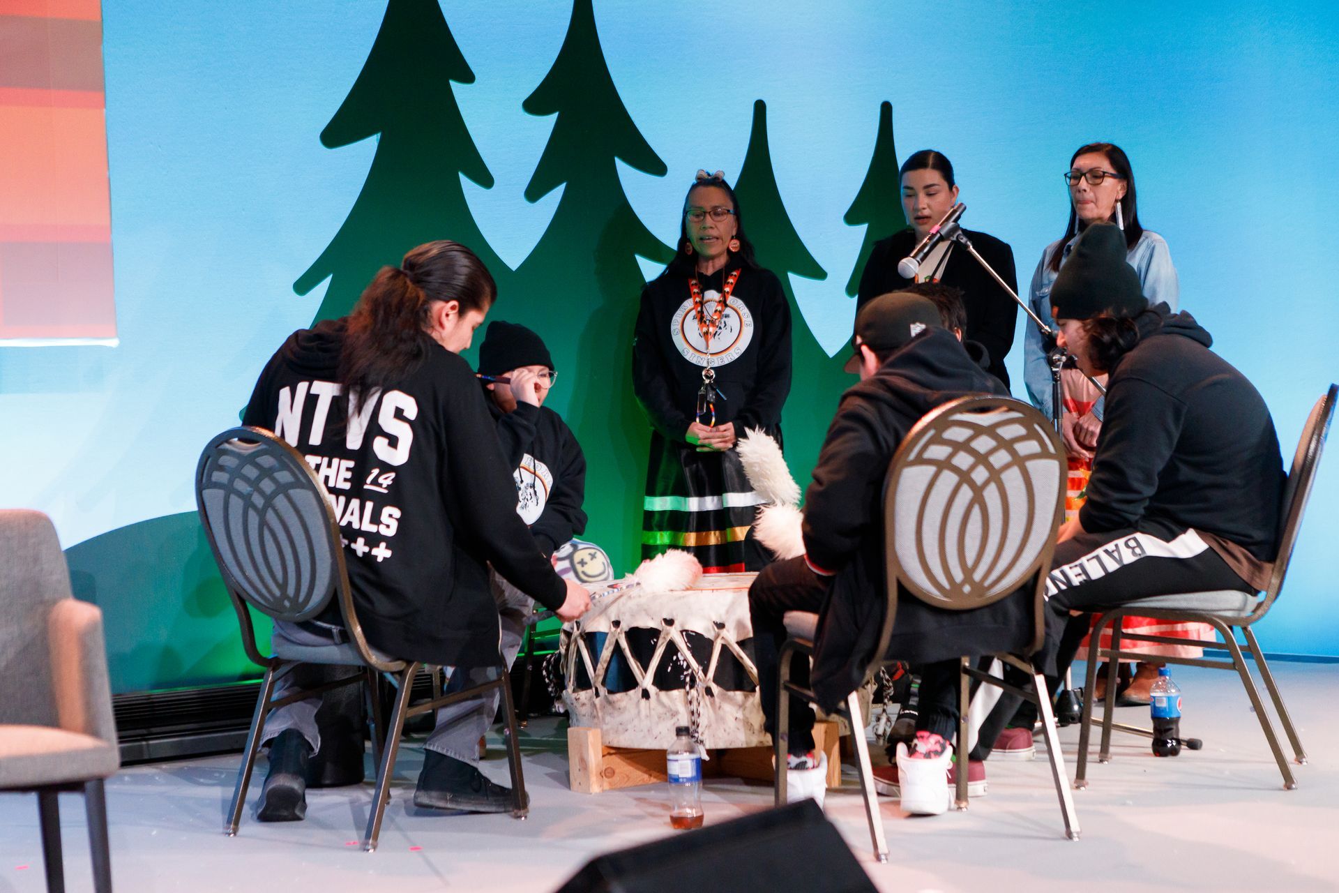 A group of people are sitting around a table on a stage.