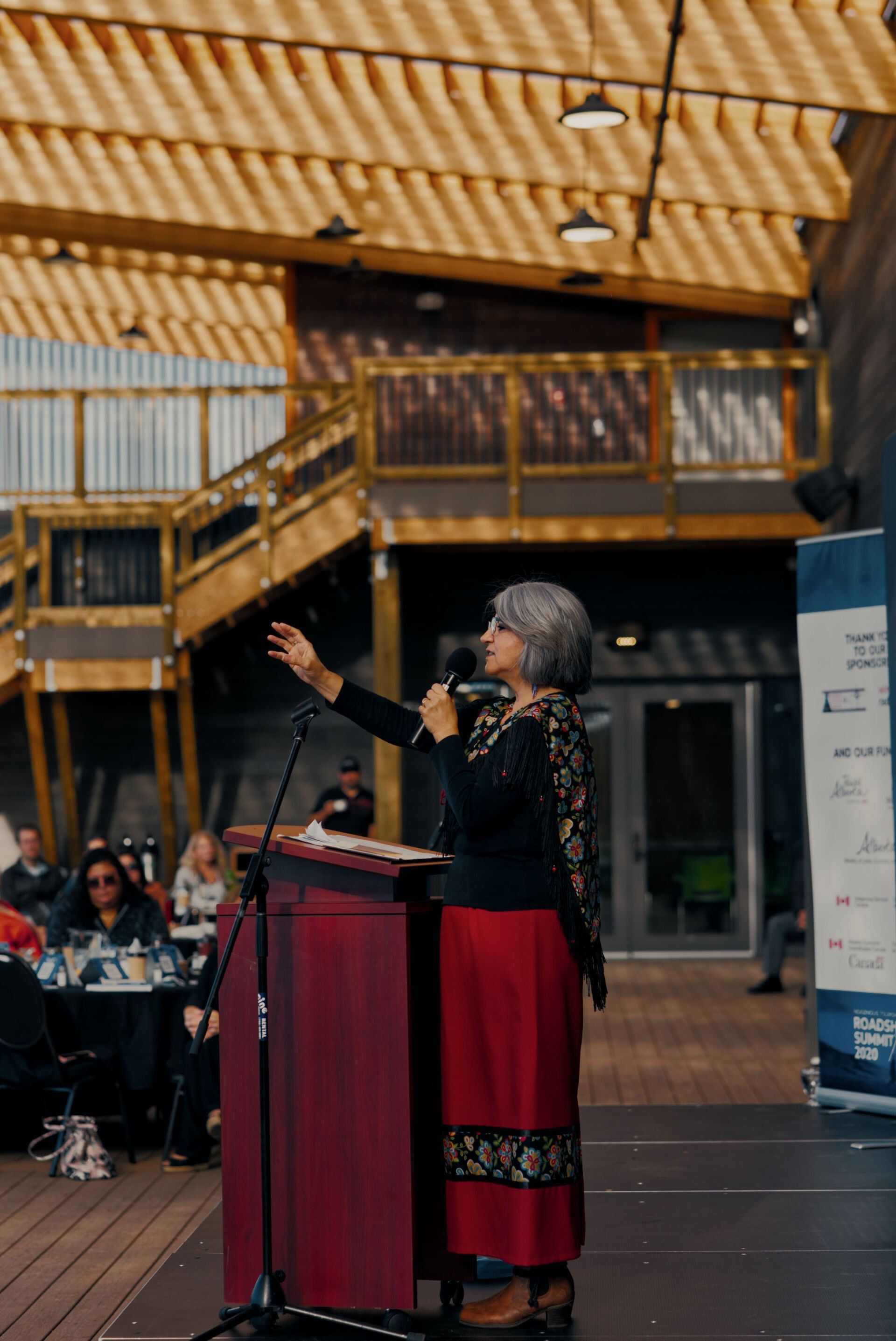 A woman is standing at a podium speaking into a microphone.