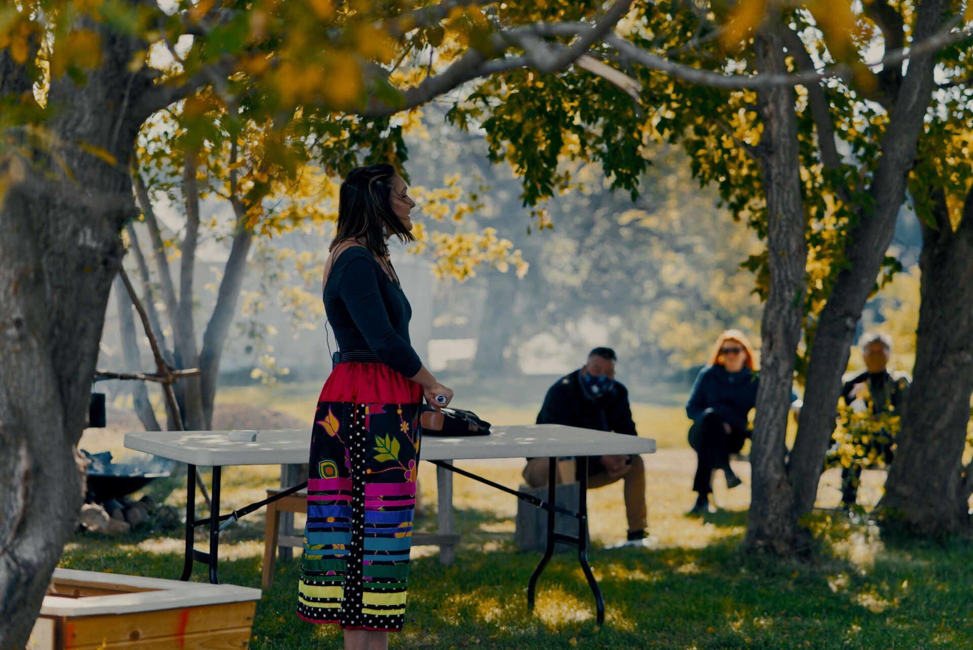 A woman is standing in front of a table in a park.
