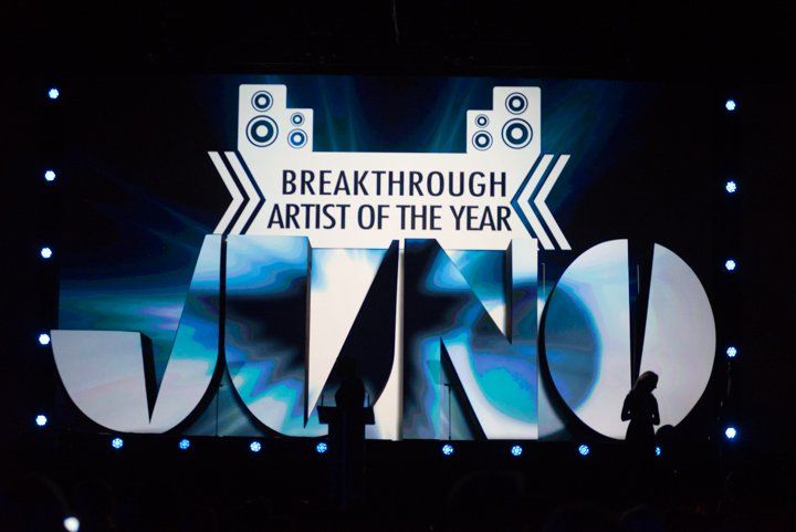 A man stands in front of a screen that says breakthrough artist of the year