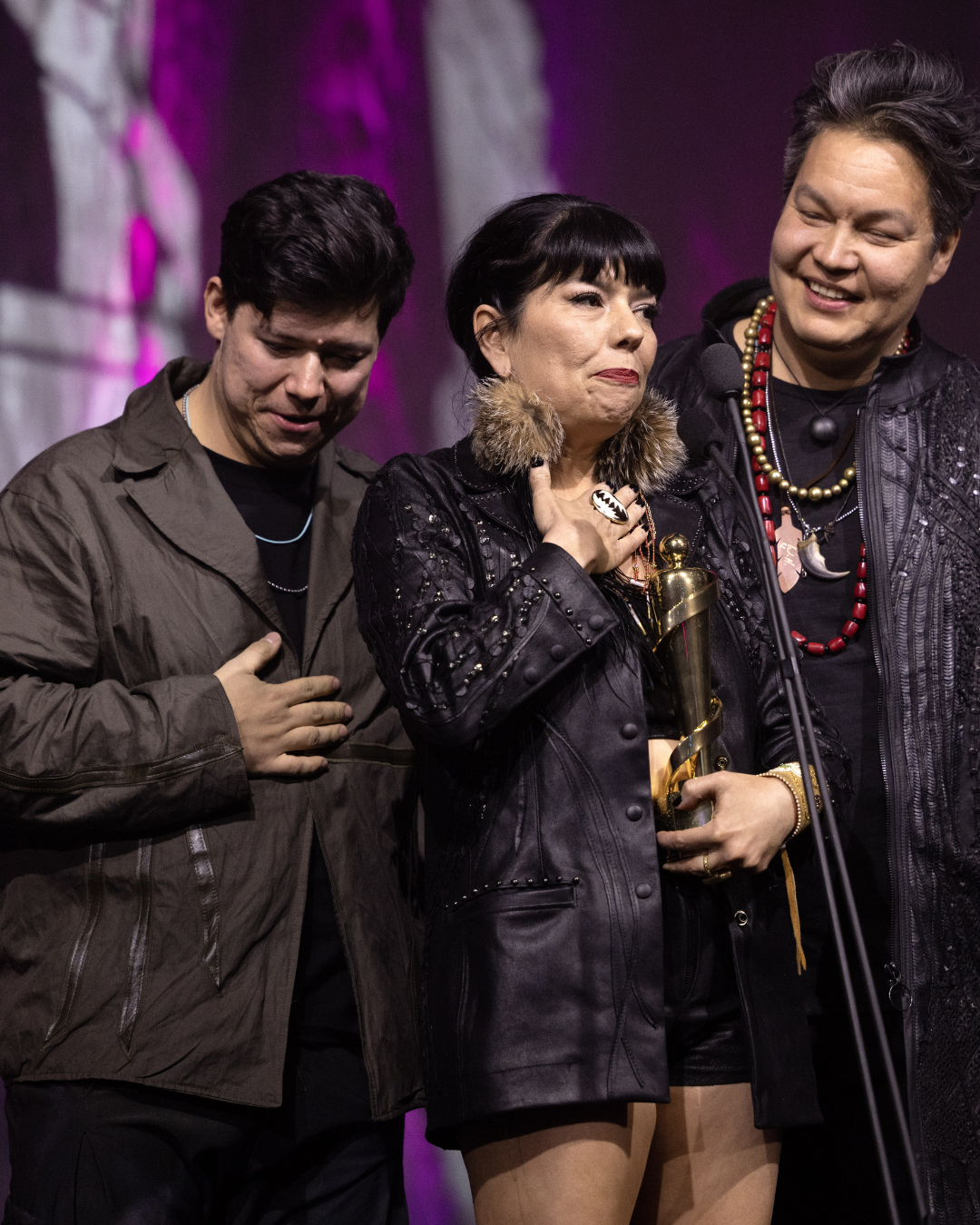 Two men and a woman are standing next to each other on a stage