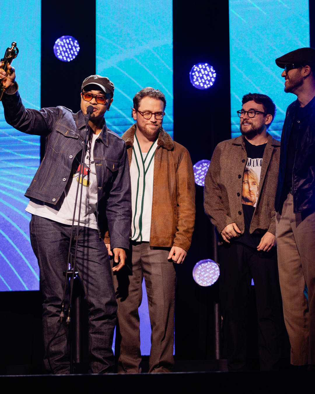 A group of men standing on a stage with one man holding a trophy