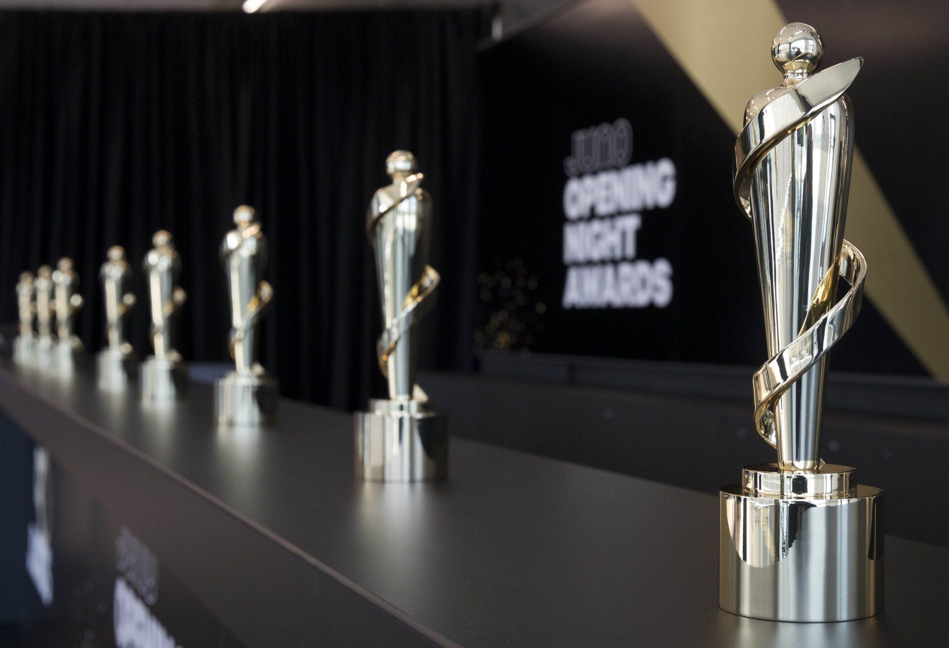 A row of trophies are lined up in front of a sign that says opening night awards