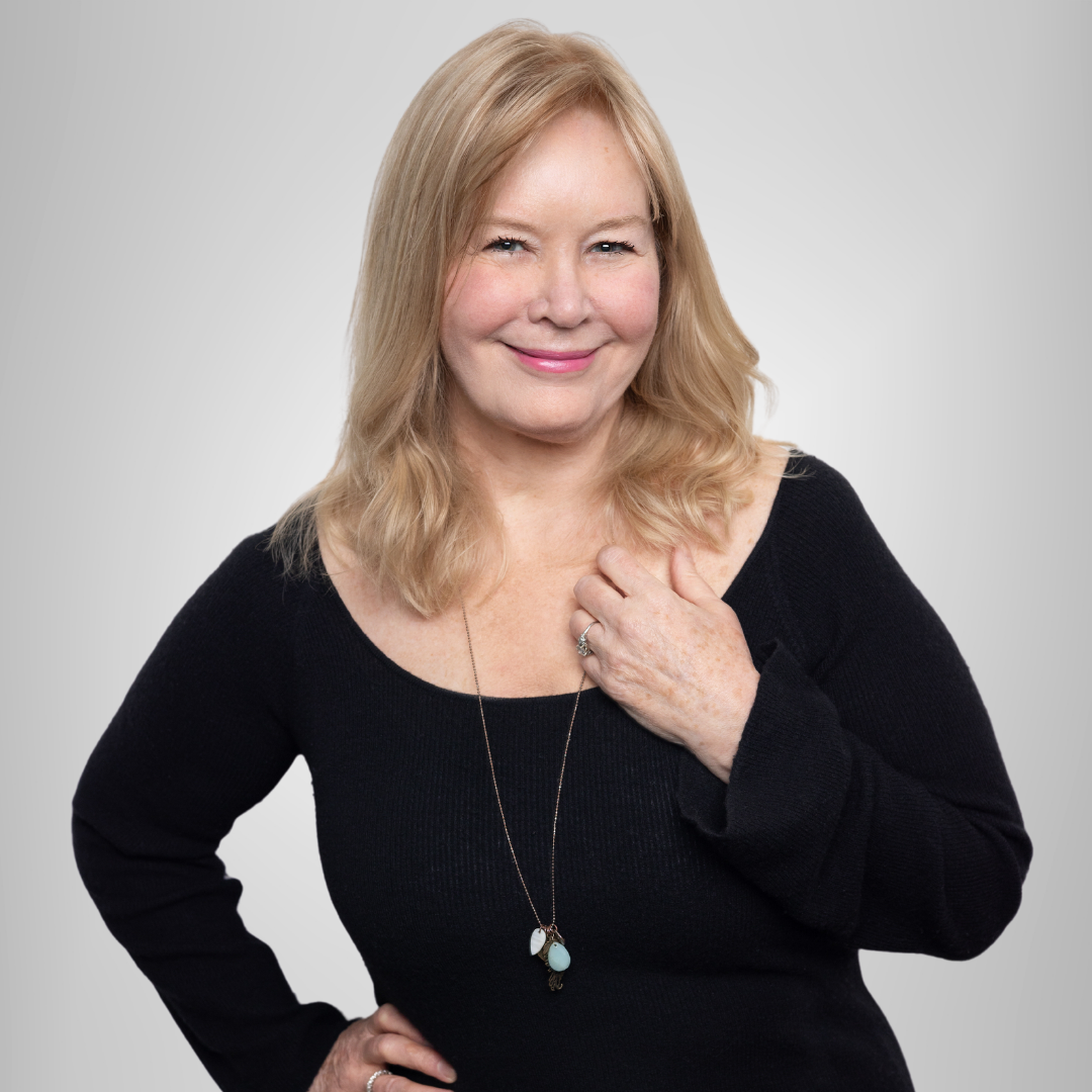A woman wearing a black sweater and a necklace smiles for the camera