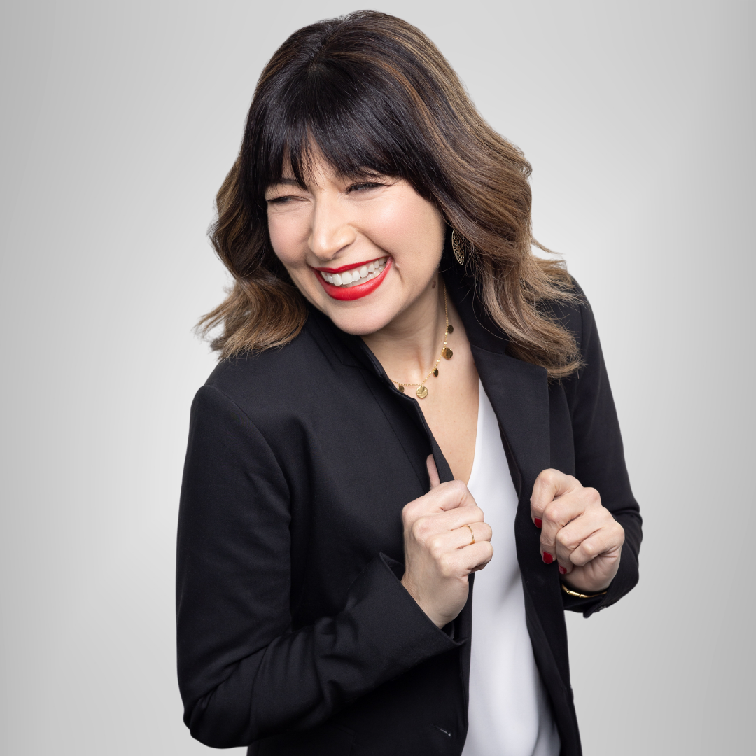 A woman in a black jacket is smiling with her eyes closed