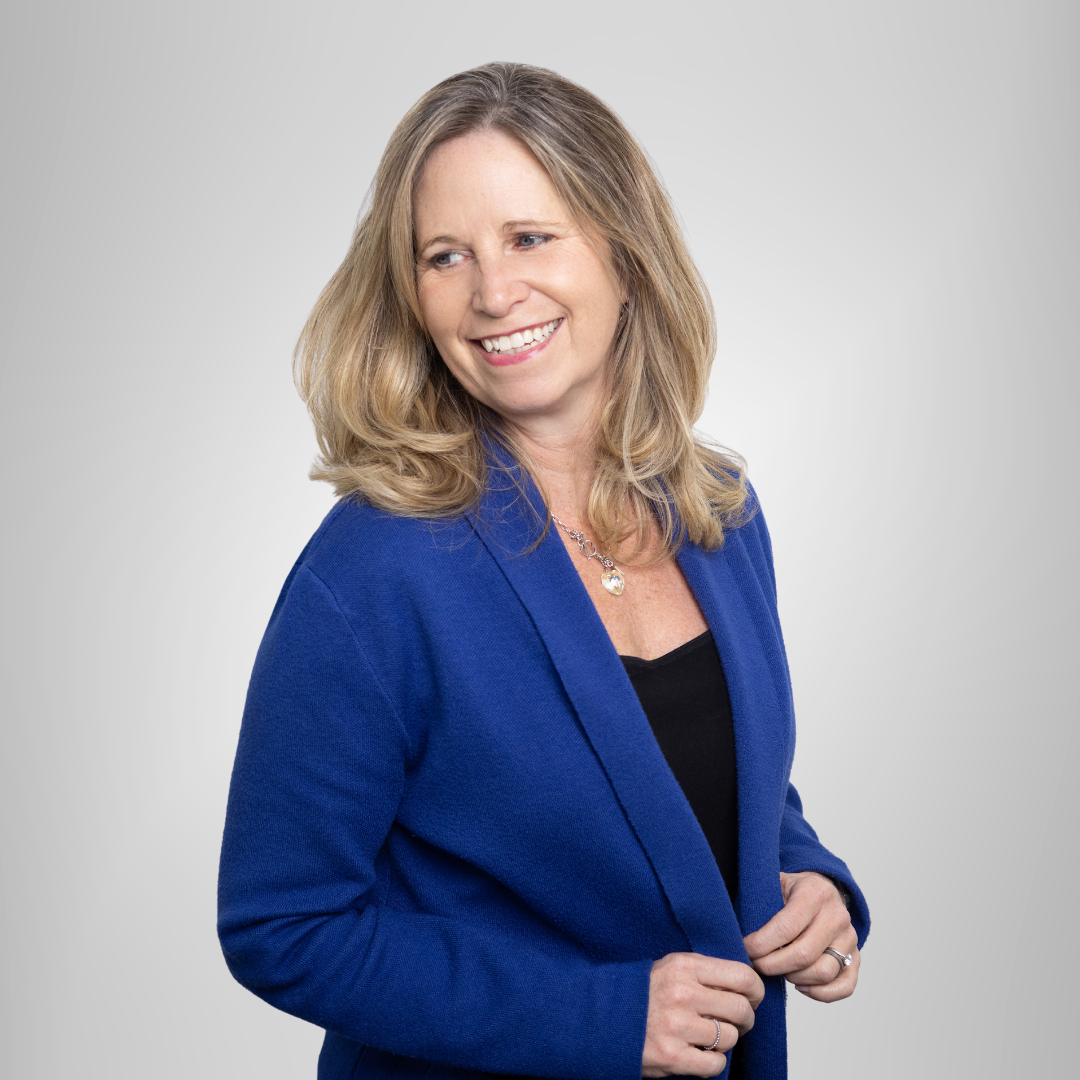 A woman is wearing a blue jacket and smiling.
