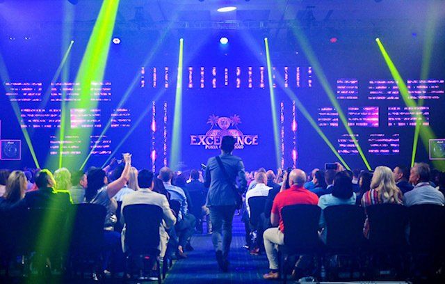 A group of people are sitting in chairs in front of a stage.