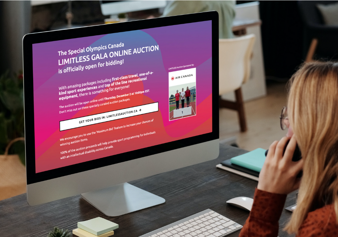 A woman is sitting at a desk in front of a computer talking on a cell phone.