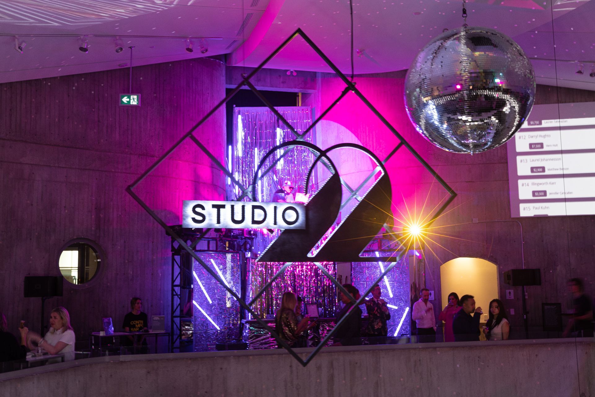 A group of people are standing in a room with a disco ball hanging from the ceiling.