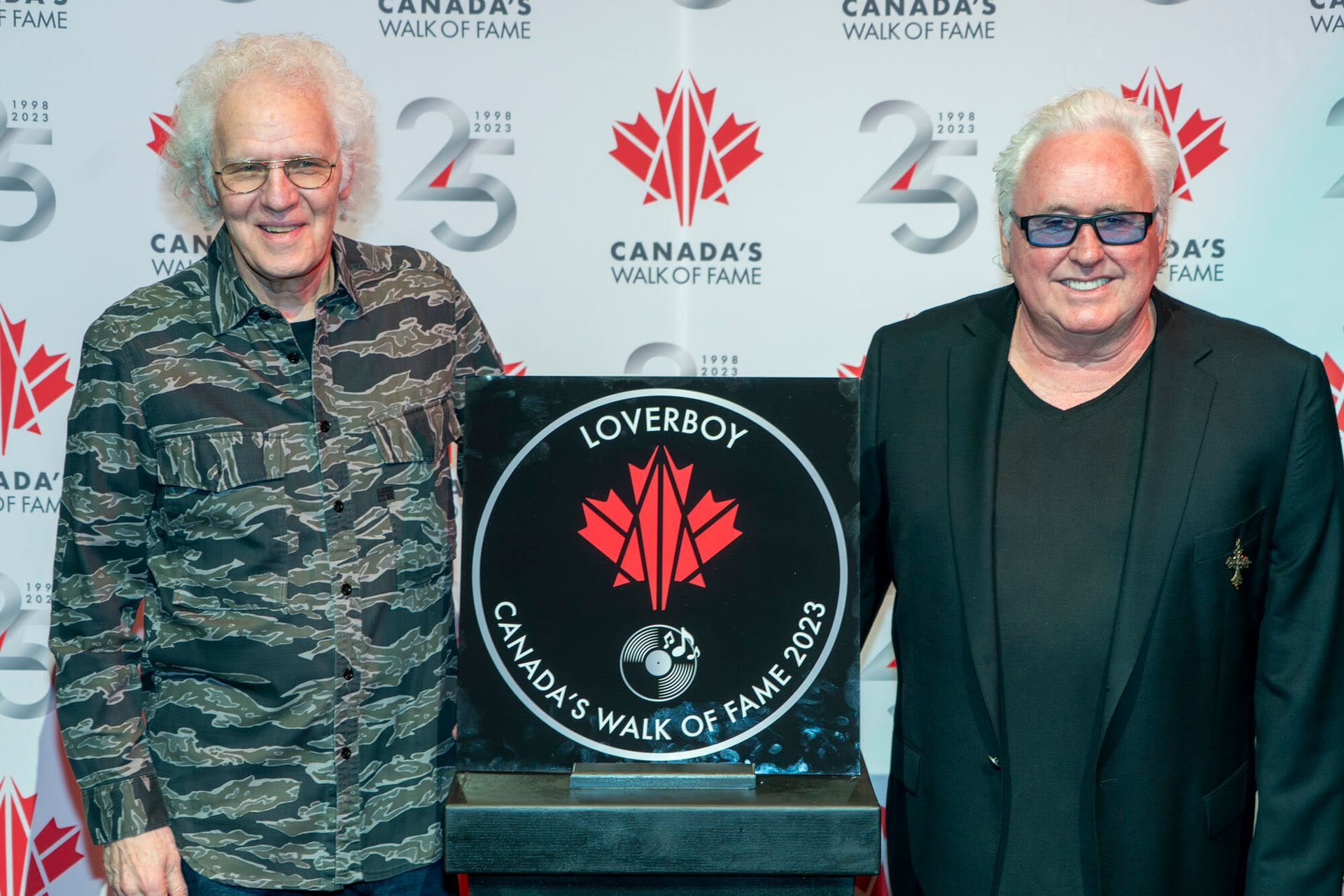 Two men are standing next to each other in front of a sign that says canada 's walk of fame.